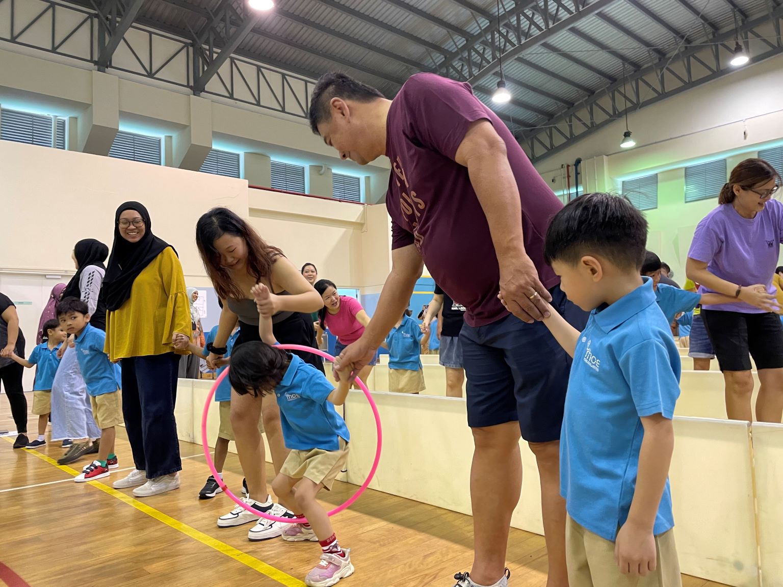 Parents and children working together to pass the hoop to the end.